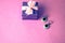 Beauty box, festive beautiful gift box with a bow with silver earrings with precious stones on a pink purple background. Flat lay