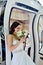 Beauty bride in bridal gown with bouquet and lace veil in the car