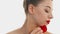 Beauty and bright red lipstick on lips. Pretty woman holds a red rose petal on her cheekbone. Profile of young light