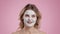 Beauty care concept. Well-groomed middle aged lady with skin lifting facial mask smiling to camera, pink background