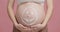 Beauty care for pregnant. Expectant lady caressing big belly with drawn cream smiling face, close up, pink background