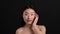 Beauty care secrets. Young korean lady with bare shoulders applying nourishing cream on face, smiling to camera