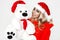 Beauty Christmas fashion model girl with white teddy bear . Long straight blonde hair in red santa hat. Sexy blonde young woman