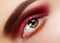 Beauty Close-up Beautiful Female Eye. Celebrate Fashion Make-up with Red Eyeshadows. Christmas or Valentines Day Makeup