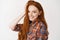 Beauty. Close-up of beautiful teenage redhead girl touching natural red hair, smiling with white teeth and looking happy