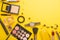 Beauty concept in a blog. Professional female make-up accessories, watch, bracelet, lipstick, powder, on a yellow background.