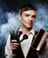 Beauty concept. Young male make up artist posing with make-up brushes and shadow palette on a dark background.