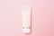 Beauty cosmetics tube; branding mock up; top view on pastel pink background. Package for hand cream or scrub.