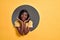 Beauty cute portrait of young african american woman. Woman posing in a circle hole in yellow background, looking at camera,