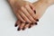 beauty delicate coffee manicure with gold sparkles with gel varnish on a white wall background