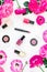Beauty desk with cosmetics, lipstick, eye shadows, nail polish and frame of pink flowers on white background. Flat lay, top view.