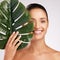 Beauty that doesnt cost the earth. an attractive young woman standing behind a plant against a studio background.