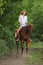 Beauty equestrian model rides a horse through a forest