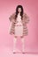 Beauty fashion elegant woman in fur coat over pink. Fashionable