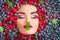 Beauty fashion model girl lying in fresh ripe berries. Face in colorful berries closeup. Beautiful makeup, juicy and lips