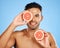 Beauty, grapefruit and skincare with a man model in studio on a blue background to promote natural treatment. Food