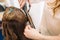 Beauty, hairstyle concept, happy young woman and hairdresser with hair iron making hairdo at hair salon. Woman Having