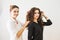 Beauty, hairstyle and people concept - happy young woman with hairdresser finishing hairdo at salon