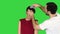 Beauty, hairstyle and people concept - young woman with hairdresser with hair spray on a green screen, chroma key.