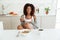 Beauty happy african woman eating by the table in kitchen