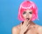 Beauty head shot. Cute Young woman with creative pop art make up and pink wig looking at the camera on blue background