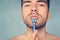 Beauty and healthcare concept. Man with bristle on blue background. Macho shaving chin with razor. Guy covered with shaving foam.