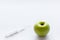 Beauty injection concept. Syringe and green apple on white background copy space