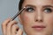 Beauty makeup. Woman shaping eyebrow with brow pencil closeup