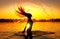 Beauty model girl splashing water with her hair. Girl silhouette over sunset sky. Swimming and splashing on summer beach