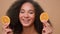 Beauty portrait African American girl woman cover eyes with two slices of orange smiling laughing diet vegetarian