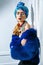 Beauty portrait of fashion model with colored headwear, blue fur coat red eyebrow and lips makeup and necklace.