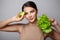 Beauty portrait of a lovely young woman showing avocado and green lettuce. Detoxification, vegetarian, healthy eating and diet