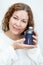 Beauty portrait of smiling attractive Caucasian curly woman holding bottle of shampoo in hands