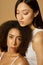 Beauty portrait of two gorgeous mixed race young women with perfect glowing skin posing together isolated over light