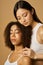 Beauty portrait of two gorgeous mixed race young women with perfect glowing skin posing together isolated over light