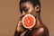 Beauty portrait of young half-naked african woman holding grapefruit