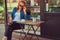 A beauty redhead girl drinks coffee, sitting near the coffee shop.