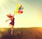 Beauty redhead girl running and jumping on summer field with colorful air balloons