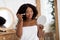 Beauty routines and makeup. Sensual young Afro woman applying powder or blusher, holding mirror at home