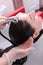 Beauty salon client washes her hair. Long hair under running water. Spa treatments for hair and scalp. Vertical photo. Top view
