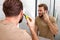 beauty, shaving. man looking at mirror, shaving beard with electric shaver