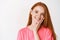 Beauty and skincare. Close-up of young redhead woman with freckles and blue eyes touching clean, no make-up skin and