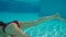 Beauty slowmotion with young woman swimming underwater in swimming pool