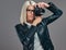 Beauty smart blonde female photographer in a white blouse and black leather jacket taking a photo at a studio.