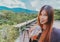 Beauty smiling female is in Cafe with forest and mountain nature background while drinking iced americano coffee