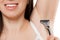 Beauty smiling young woman holding razor blade shaving armpit sk