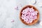 Beauty, spa and wellness composition of perfumed pink flowers water in wooden bowl and candles on stone table. Aromatherapy.