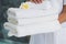 Beauty therapist holding pile of fresh white towels