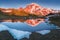 The beauty & tranquility of a summer evening at Mount Rainier National Park. Tall evergreen trees that line an alpine lake & blue