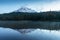 The beauty & tranquility of a summer evening at Mount Rainier National Park. Tall evergreen trees that line an alpine lake & blue